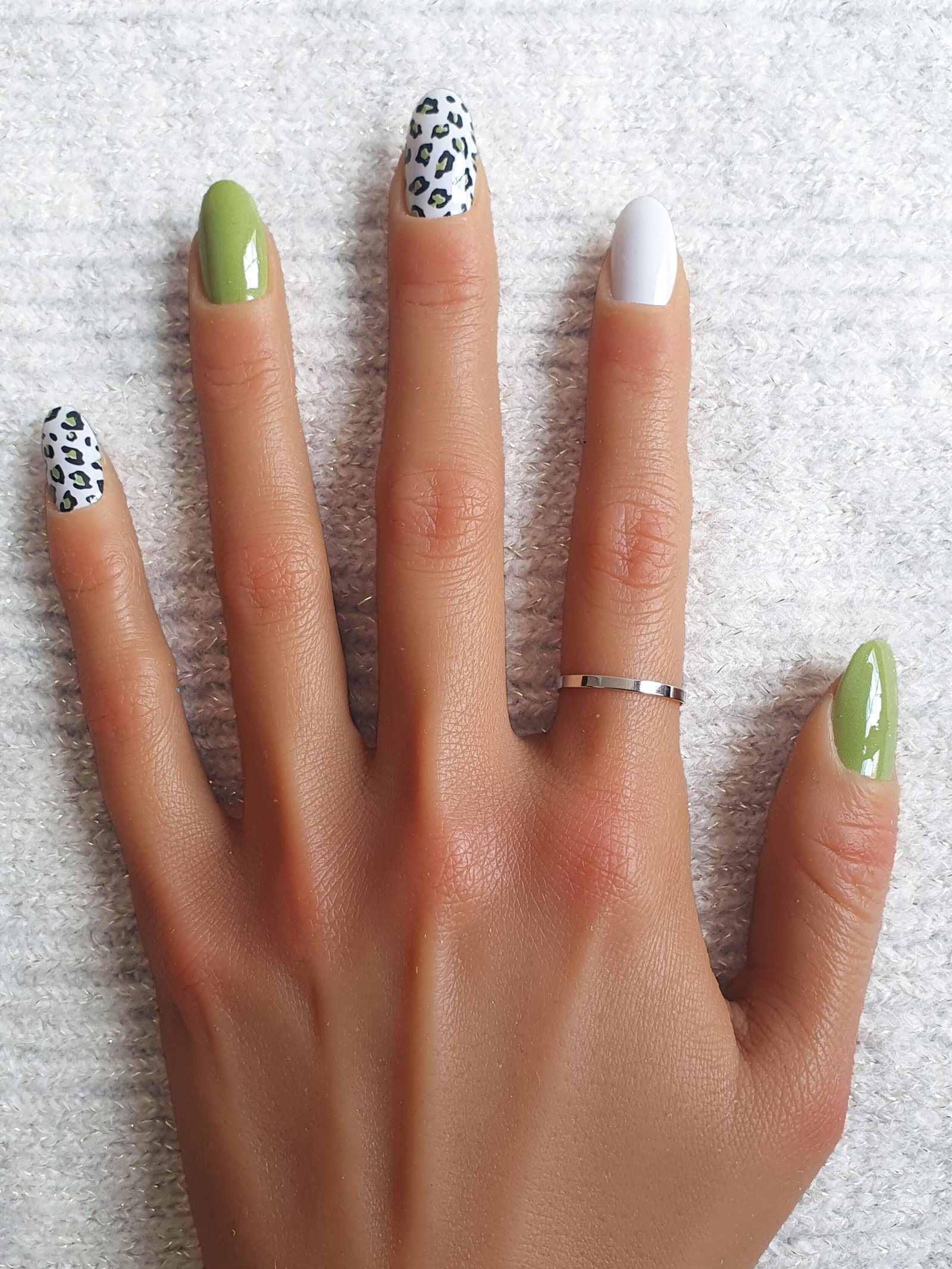 Manucure avec autocollants pour ongles léopard et couleurs vert et blanc.