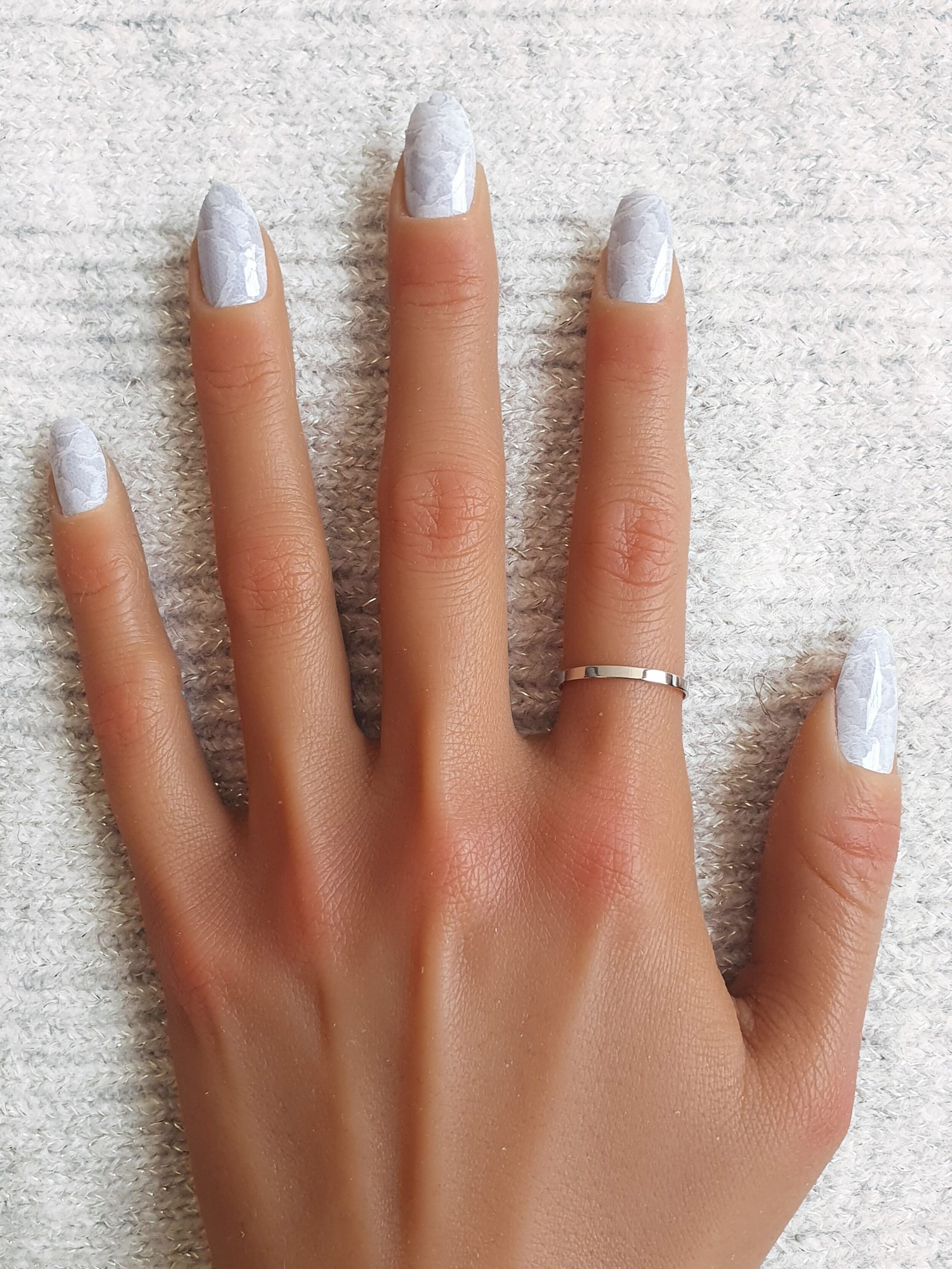 Main avec un nail art dentelle blanc sur fond clair