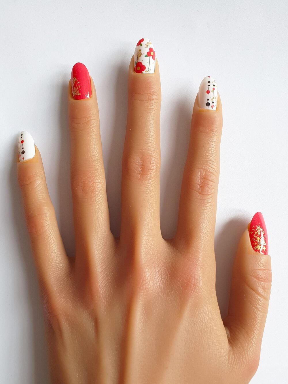 Ongles décorés avec des stickers fleurs rouges et dorés, parfaits pour une manucure fleurs tendance.